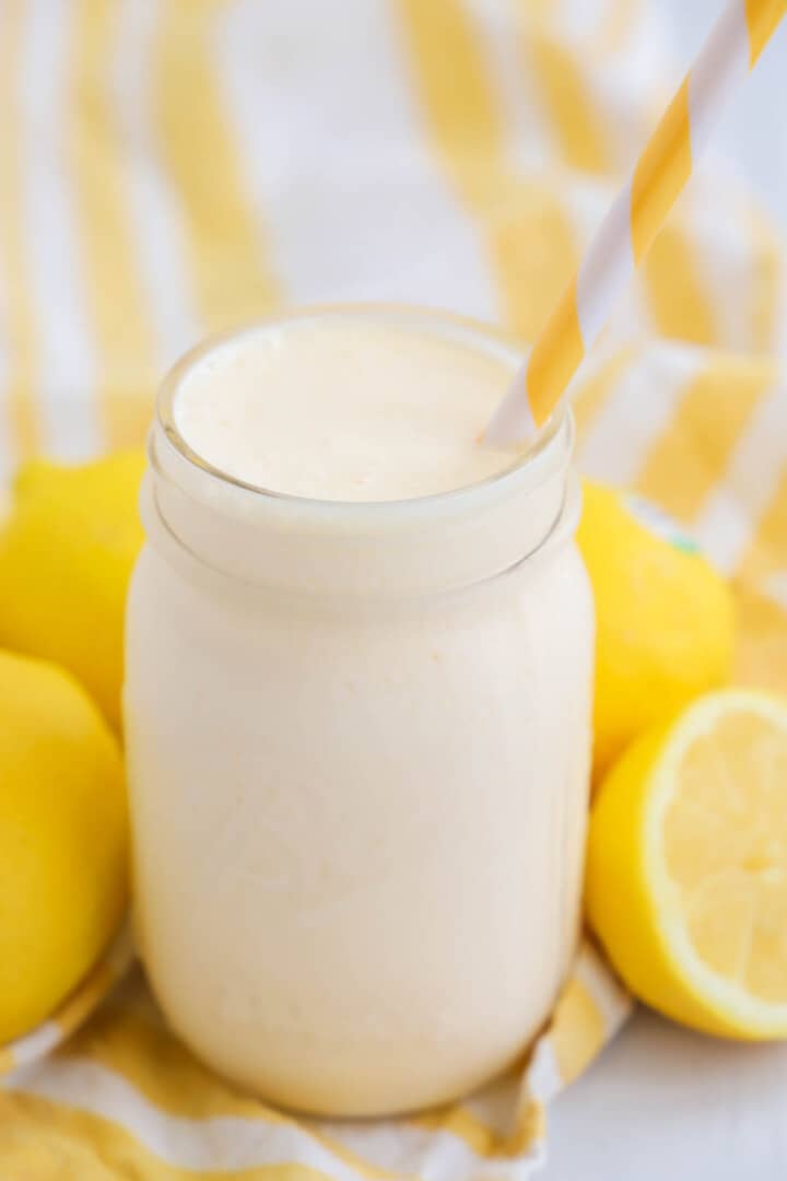 frosted lemonade in glass with lemons on the side.