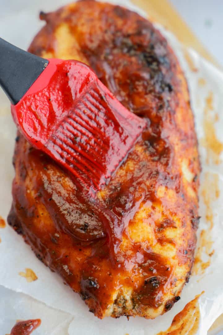 brushing BBQ sauce on the grilled chicken.