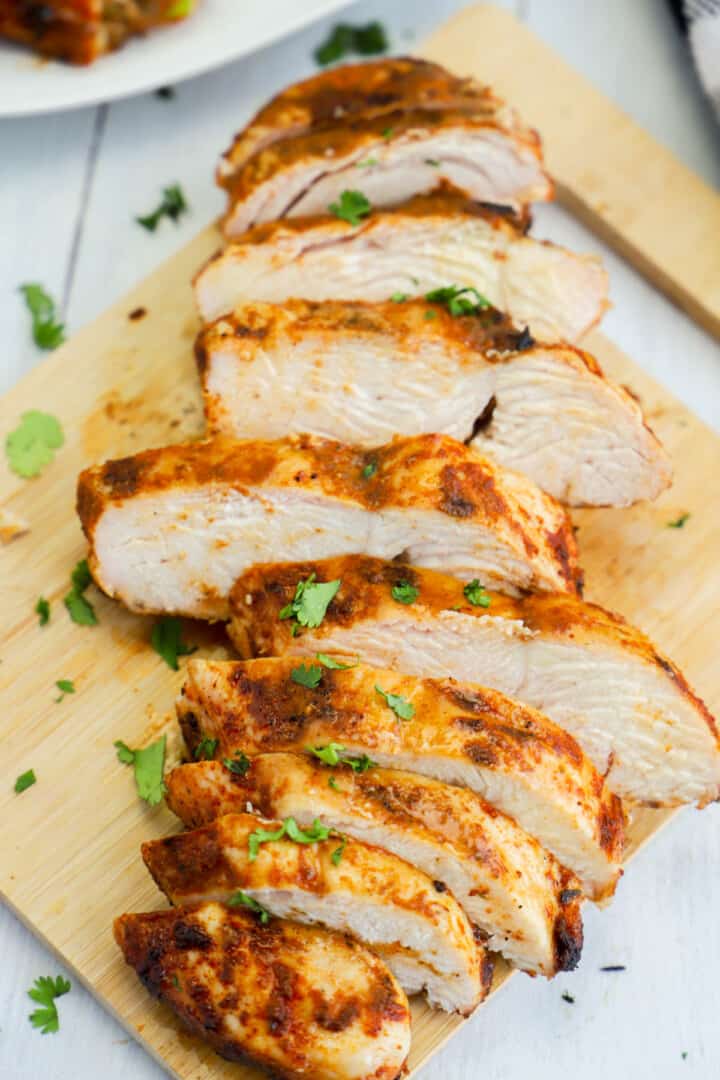 Grilled Chicken Breast sliced on a wooden cutting board.