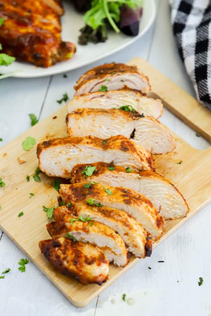 closeup of sliced chicken breast on wooden board.