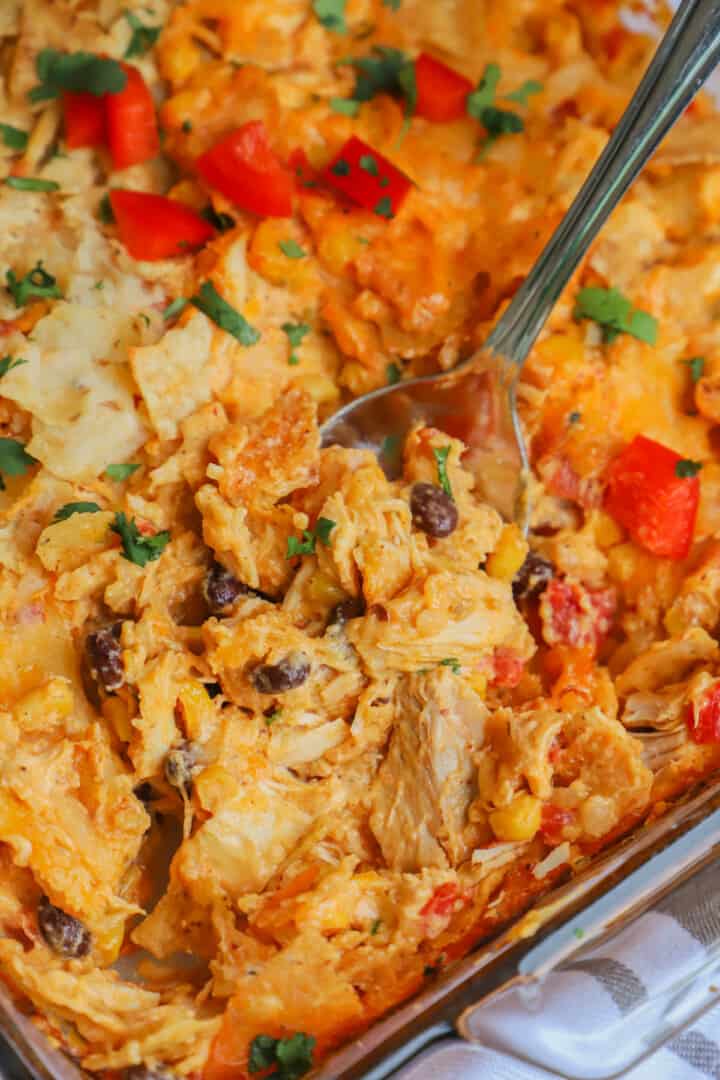 closeup of Mexican chicken casserole being scooped by a metal spoon.