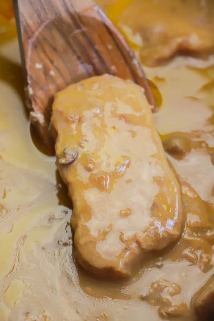 Slow Cooker Smothered Pork Chops being served with a wooden spoon.