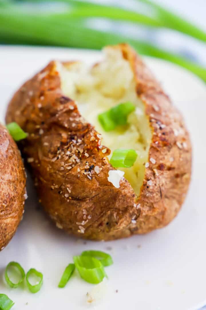 Air Fryer Baked Potato on white plate with chives.