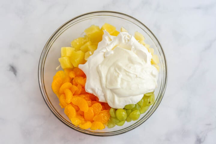 adding the yogurt and cool whip to the fruit salad.