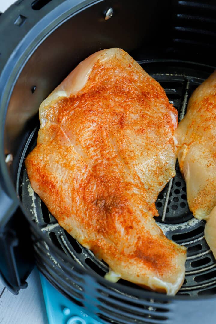 adding chicken breasts to the air fryer.