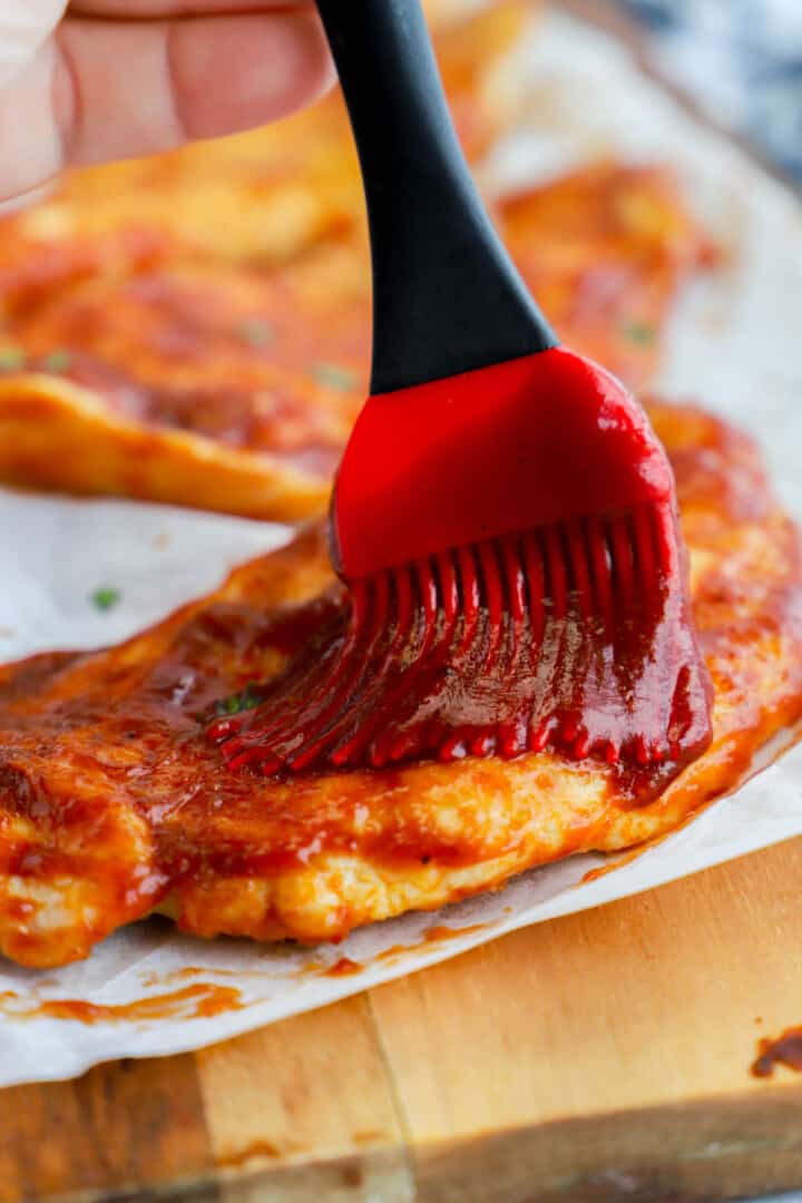 brushing the chicken breasts with BBQ sauce.