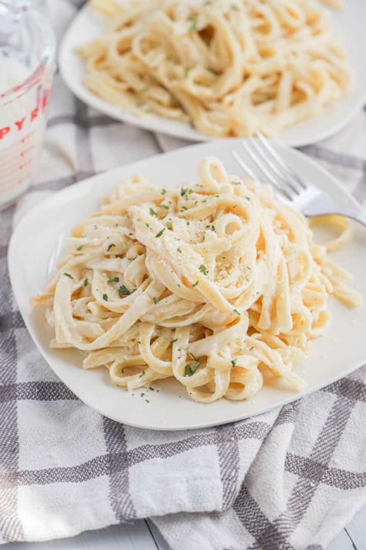 Homemade Alfredo Sauce with noodles on white plate.