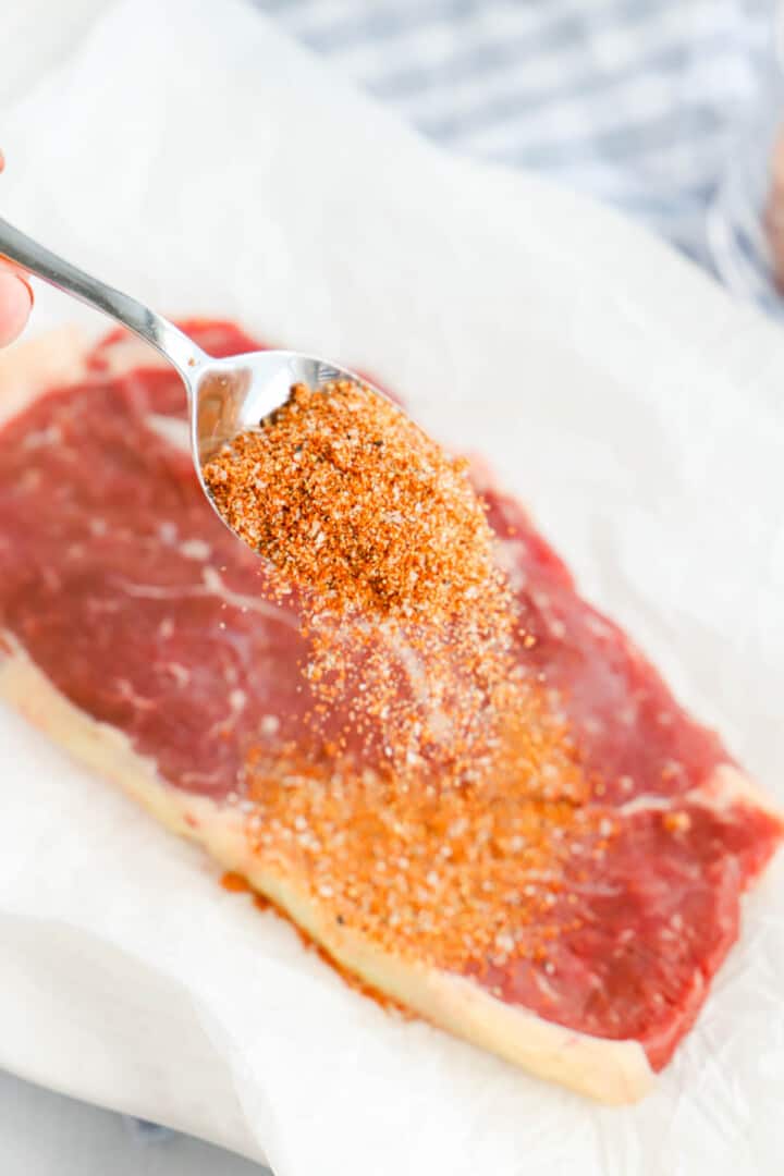 spreading Steak Rub on a steak.