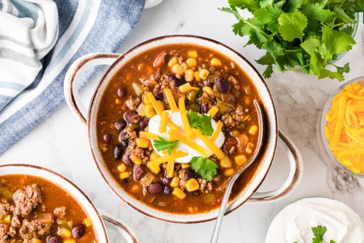 taco soup in a white bowl with handles. 