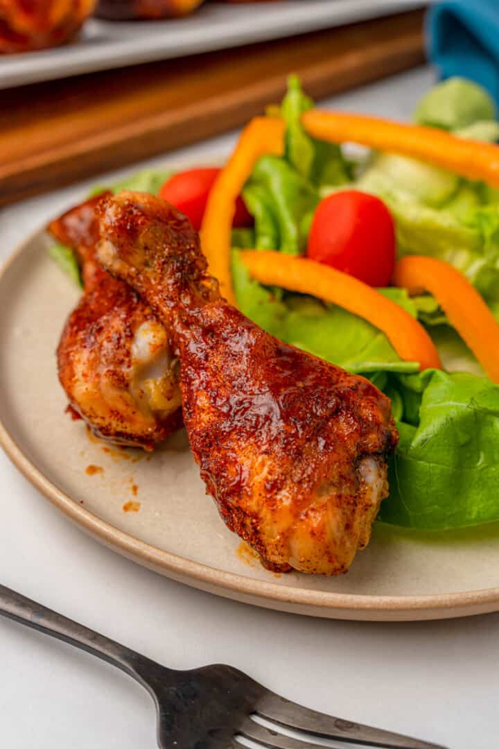 baked BBQ drumsticks on plate with salad.