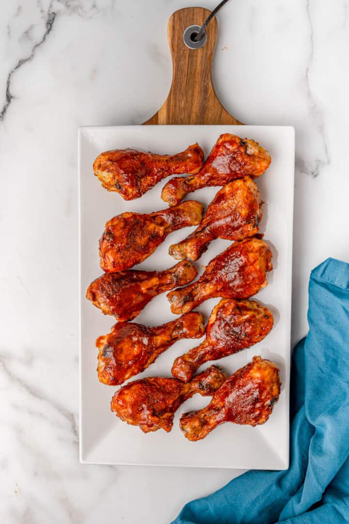 BBQ drumsticks on white serving tray.