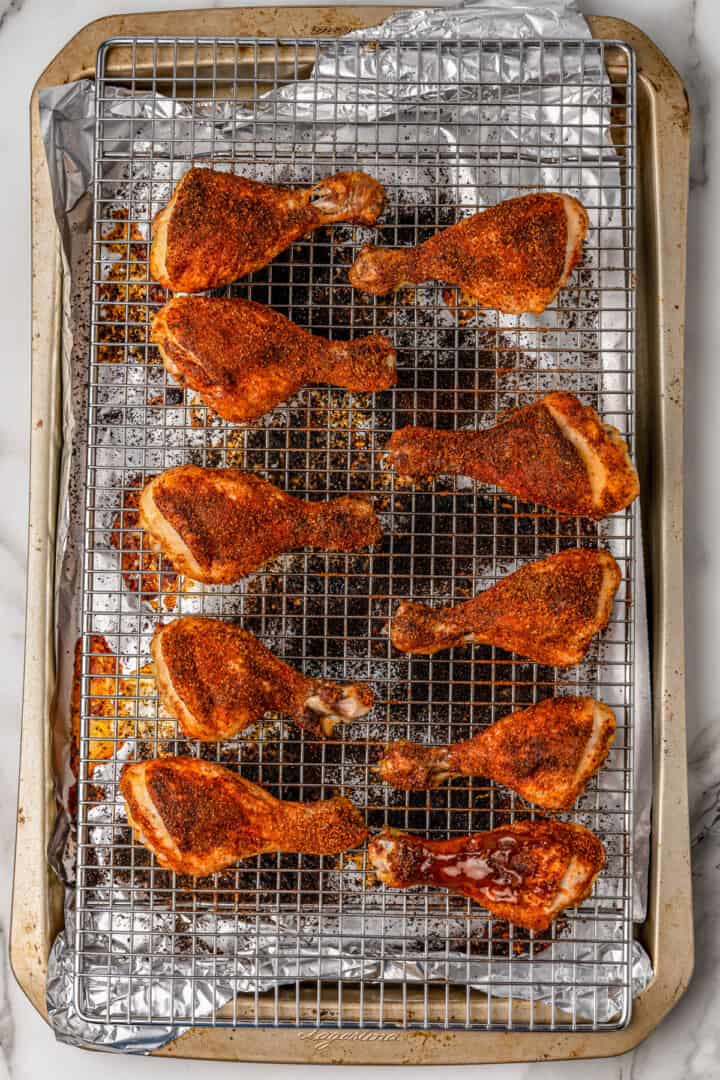 seasoned drumsticks on wire rack on baking sheet.