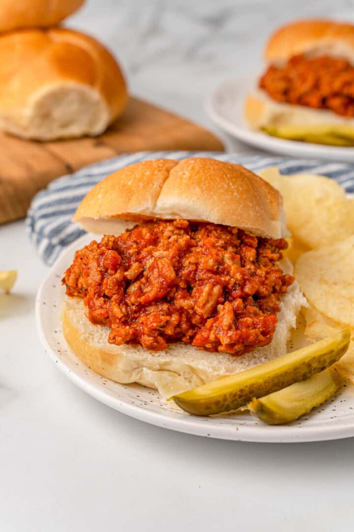 Ground Turkey Sloppy Joes on plate with chips and pickles.