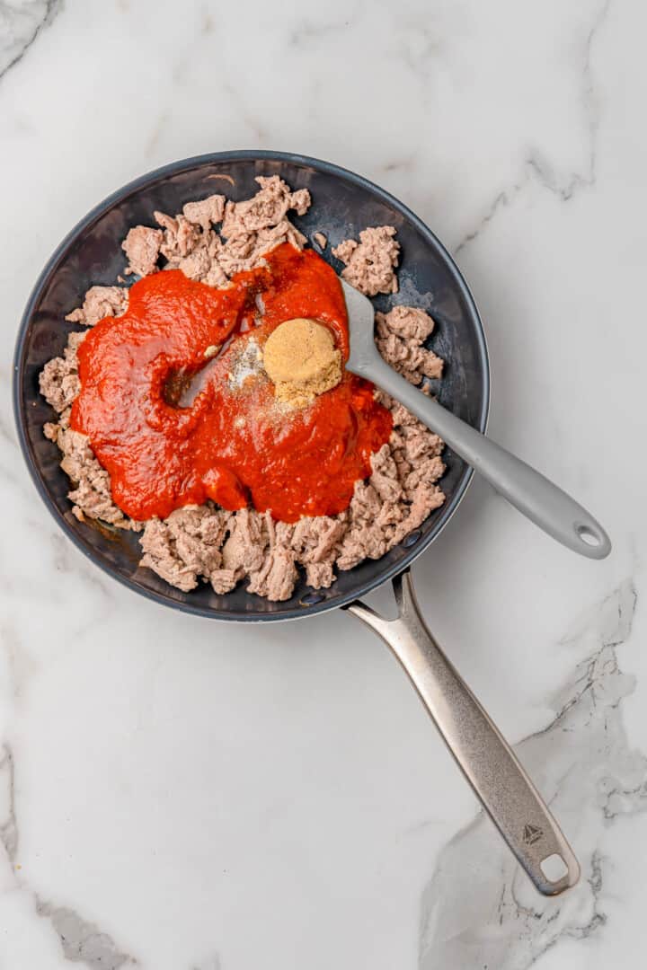 adding sauce and seasoning to the ground turkey.