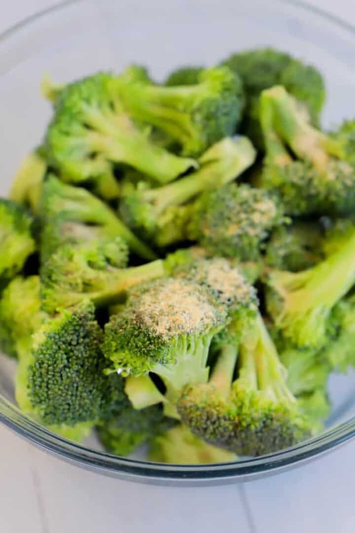 seasoning the broccoli before roasting.
