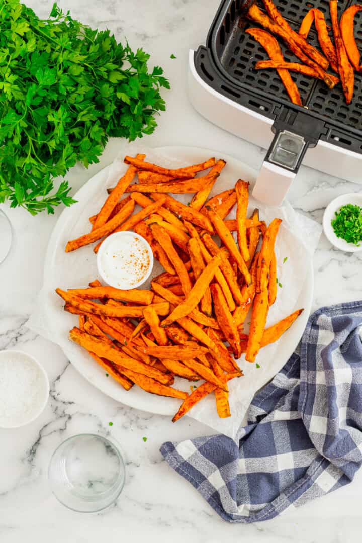 air fryer sweet potato fries on white plate with dip.