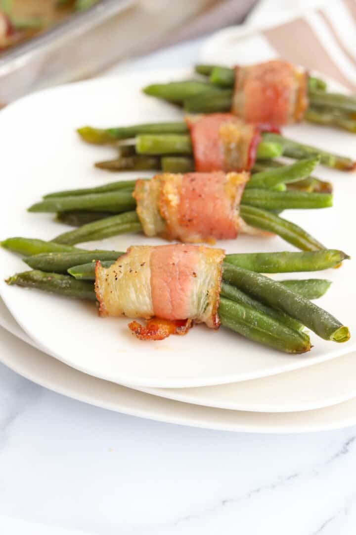 Bacon Wrapped Green Beans on stacked white plates.