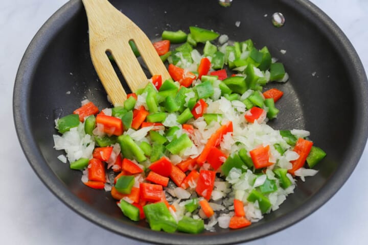 cooking the peppers and onions on a skillet.