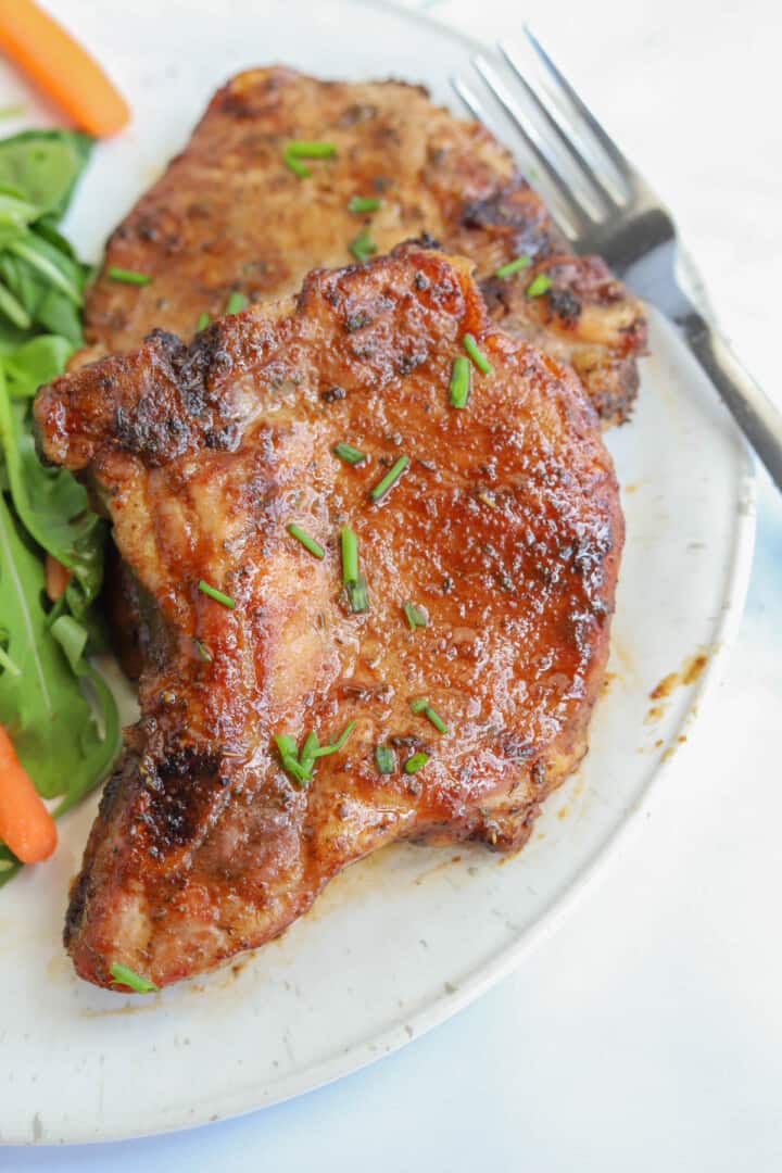 Pork Marinade on pork chops on white plate with salad.