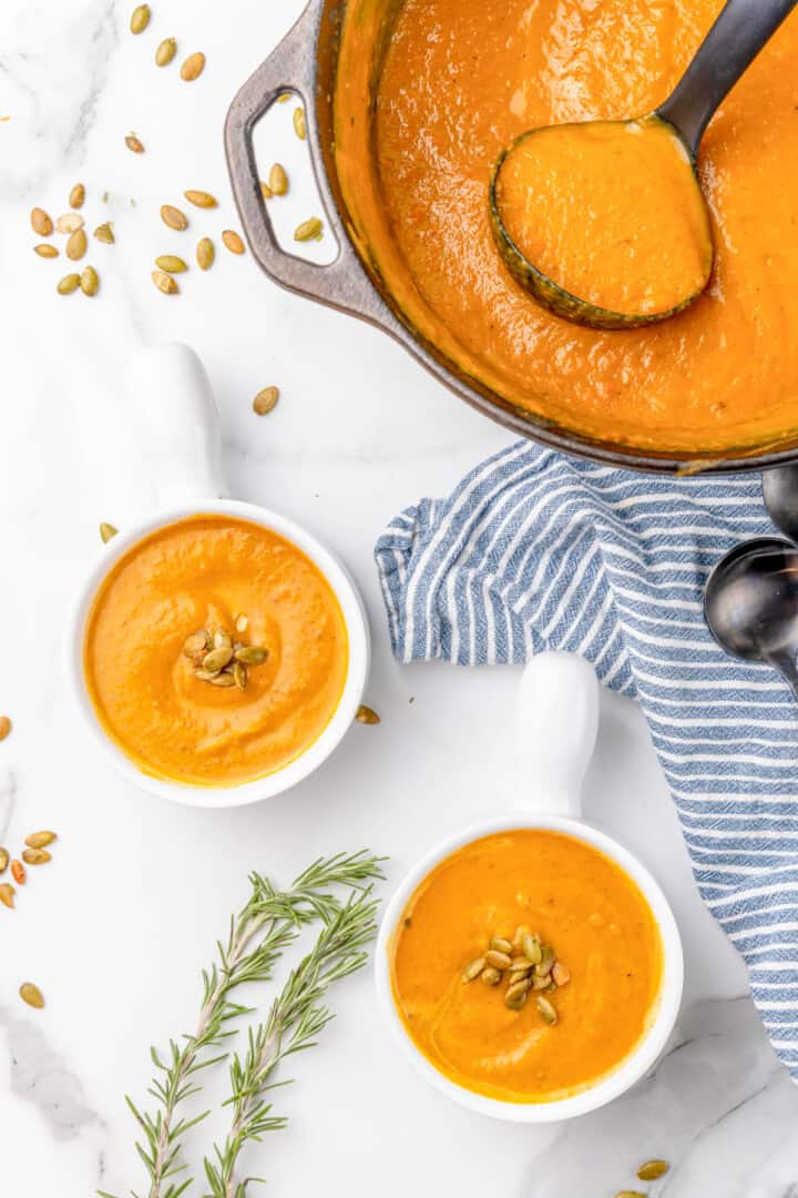 butternut squash soup in pot and served in white bowls.
