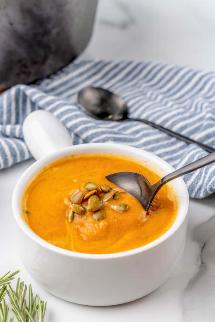 butternut squash soup in white bowl with spoon.