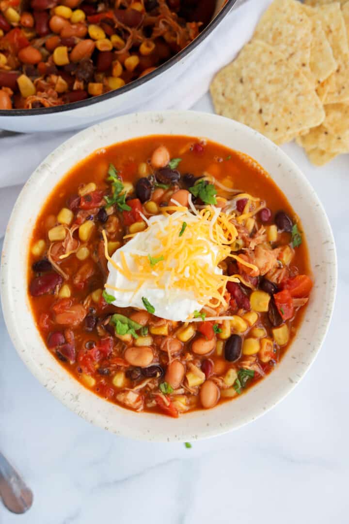 7 Can Taco Soup in white bowl topped with sour cream and cheese.