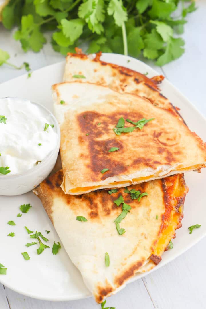 Air Fryer Quesadillas on white plate with sour cream.