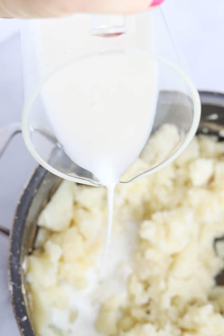 adding the buttermilk to the mashed potatoes.