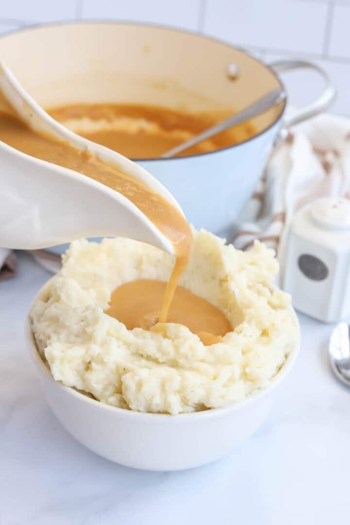 pouring gravy on top of mashed potatoes.