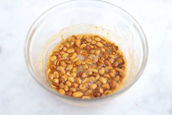 melted butter, sugar and peanuts in clear bowl.