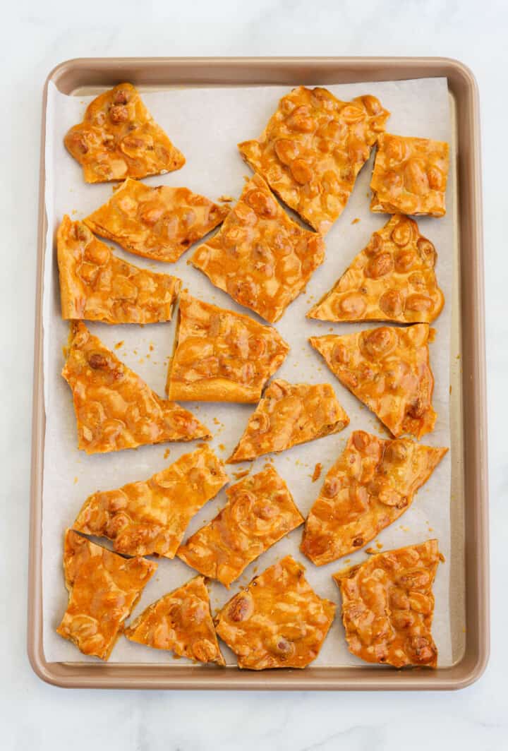 peanut brittle broken into pieces on baking sheet.