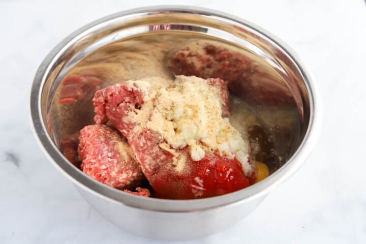 making the meatloaf meat by mixing the meat and ingredients together.