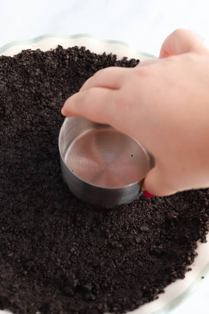 pushing crushed Oreos into the pie pan to make crust.