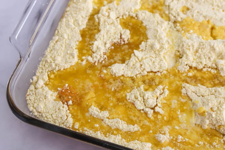 pouring melted butter on top of the cake mix.