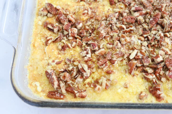 adding crushed pecans to the top of the cake.