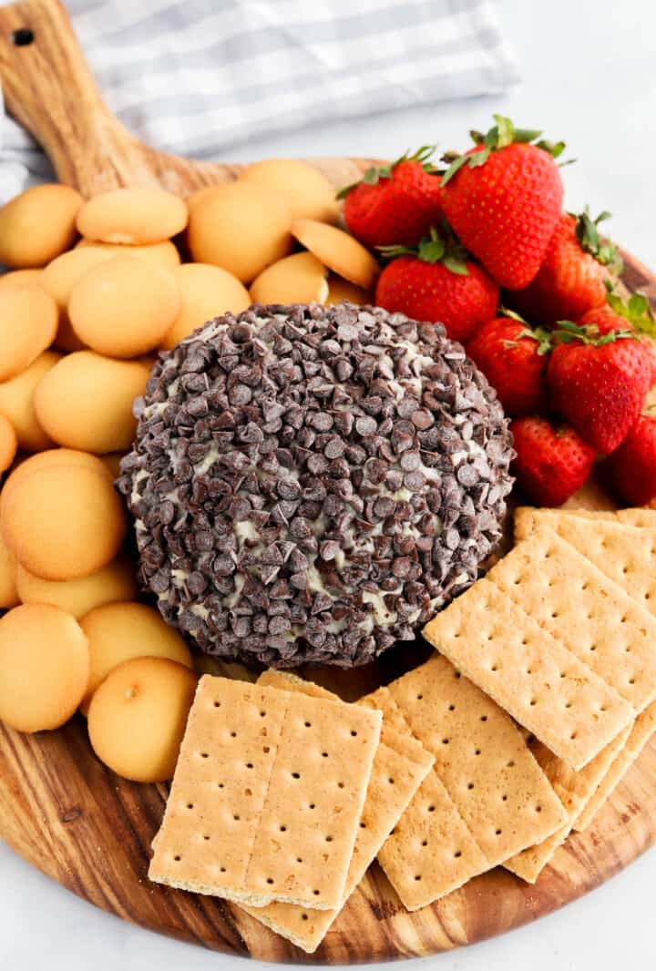 Chocolate Chip Cheese Ball on serving board with graham crackers, vanilla wafers and strawberries.