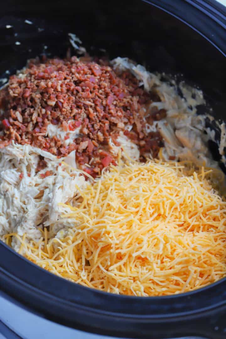 adding the bacon and cheese to the crock pot.