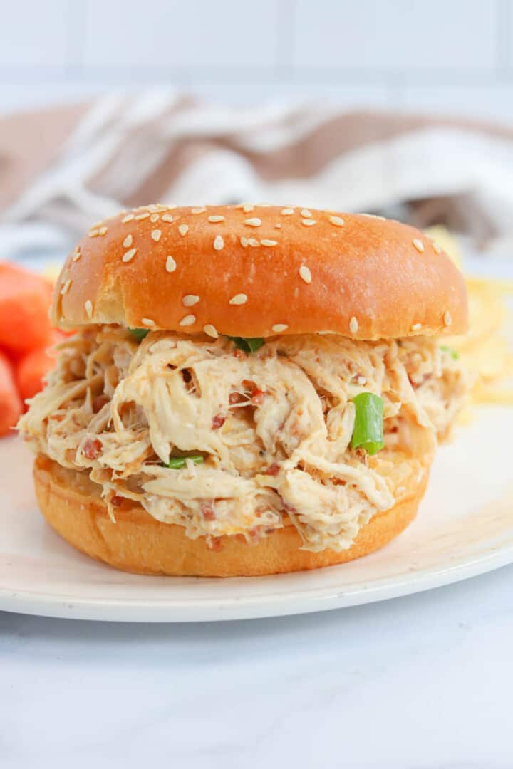 closeup of crack chicken sandwich on white plate.