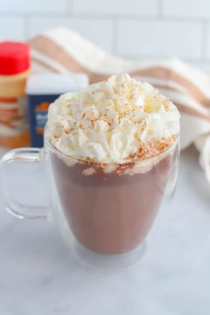 Pumpkin Spice Hot Chocolate in clear mug with whipped cream.
