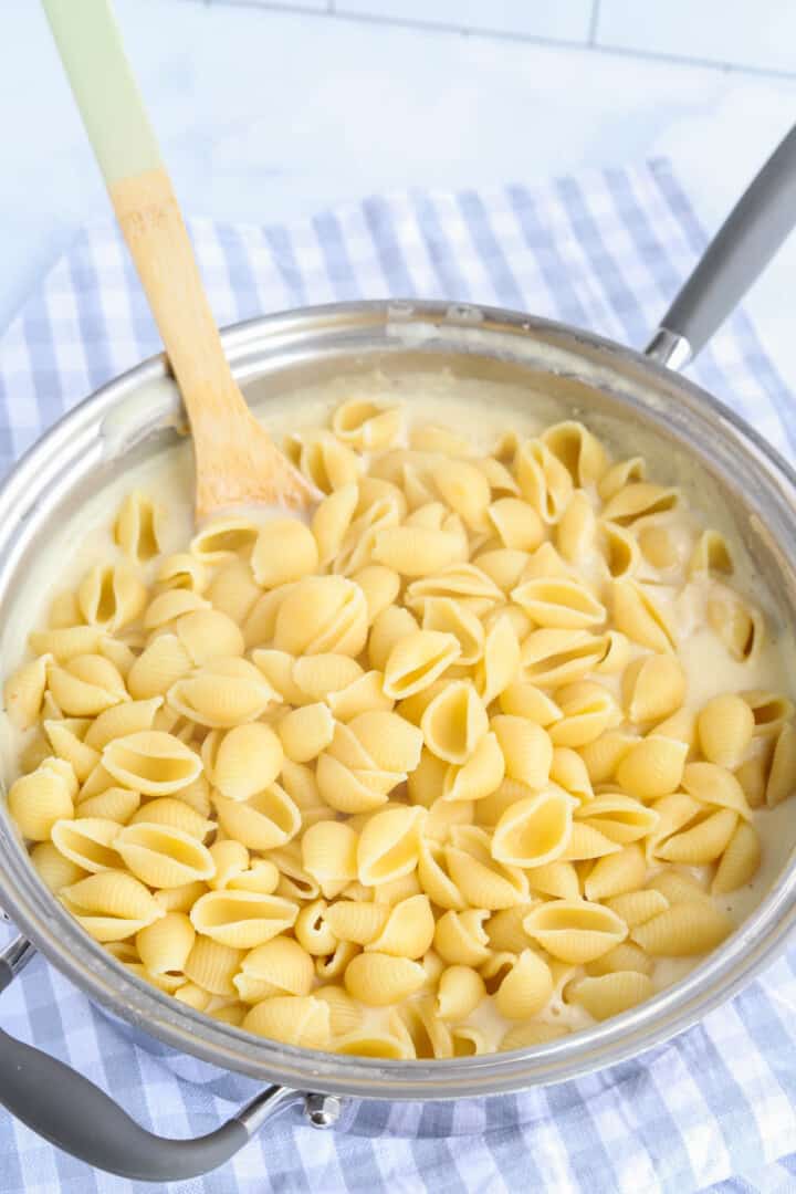 adding noodles to the cheese sauce.