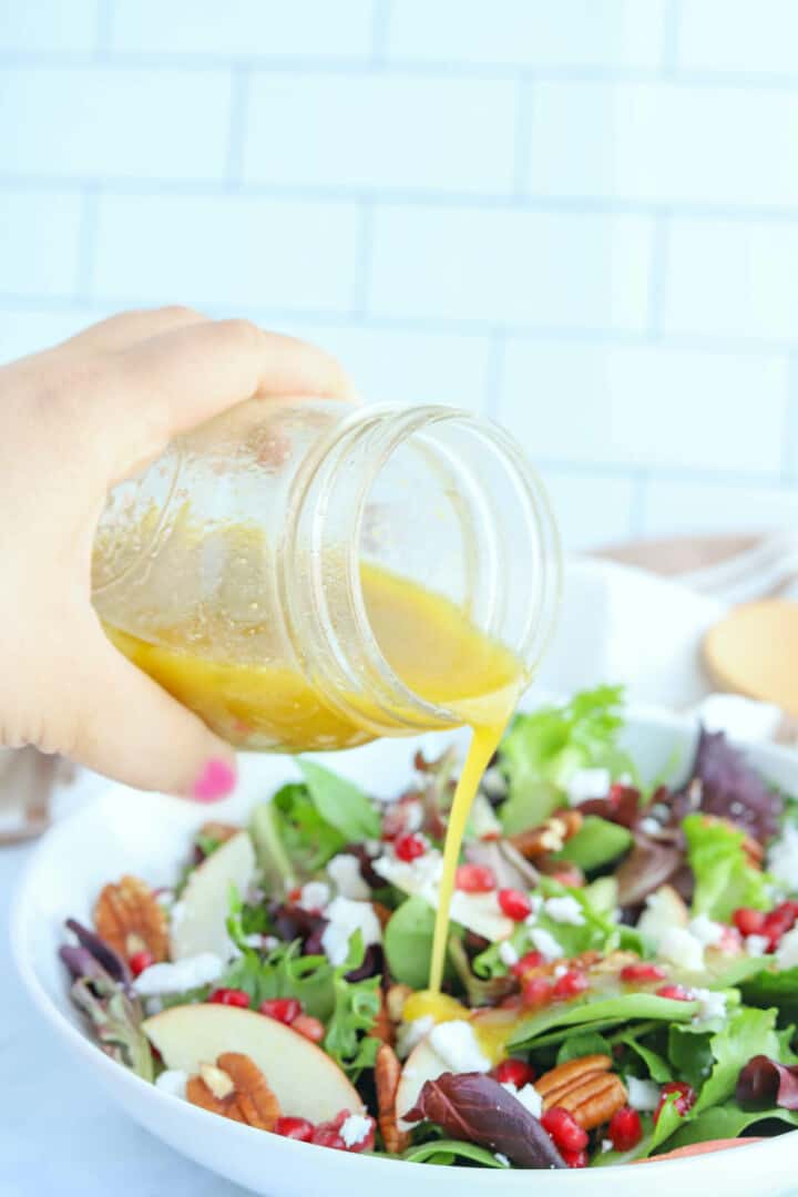 pouring dressing on top of salad.