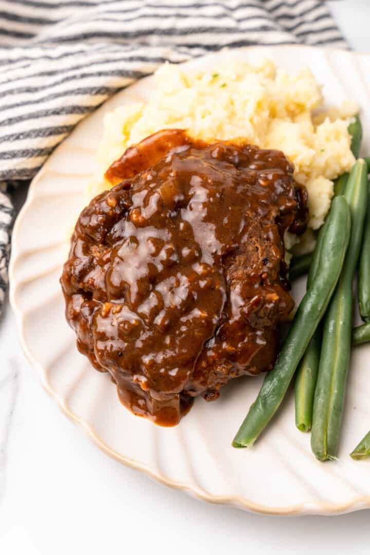 closeup of Salisbury steak on plate with sides.