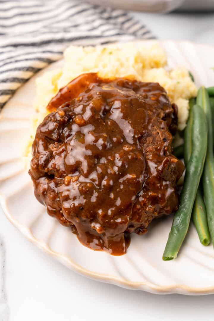 Easy Salisbury Steak on plate with mashed potatoes and green beans.