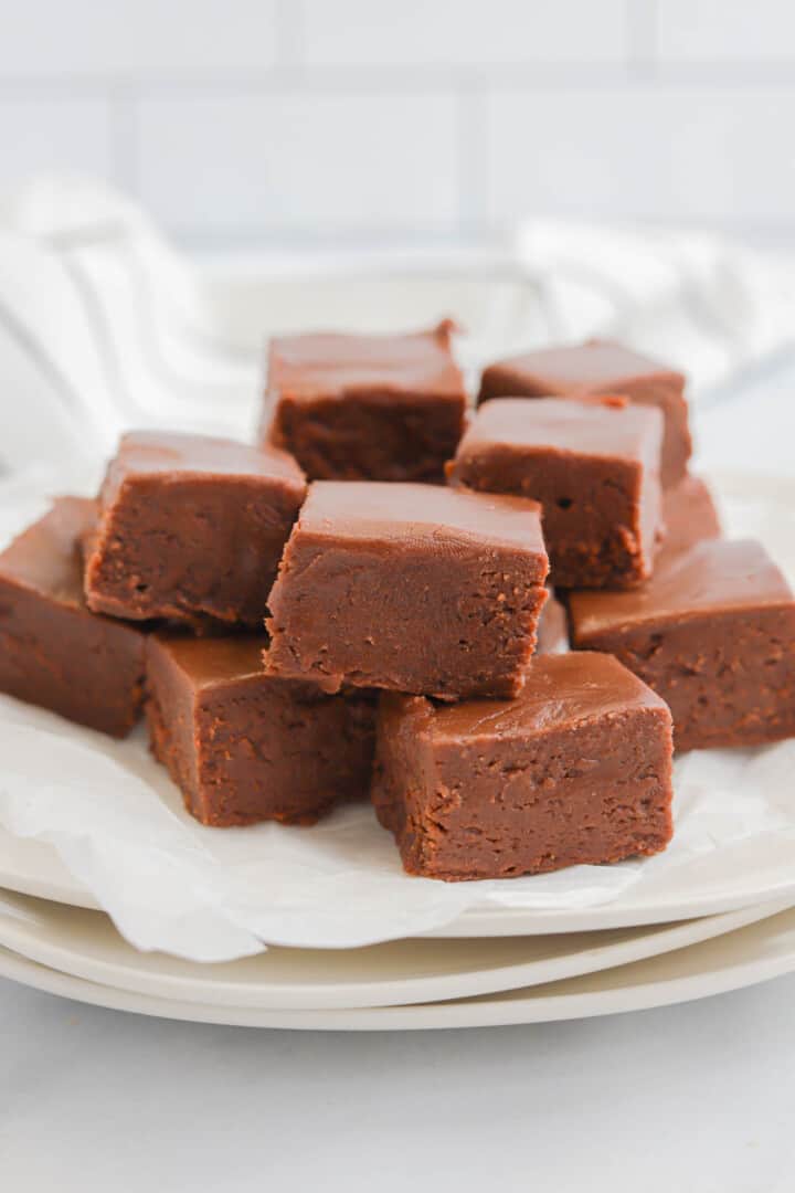 2 Ingredient Fudge stacked on white plates.