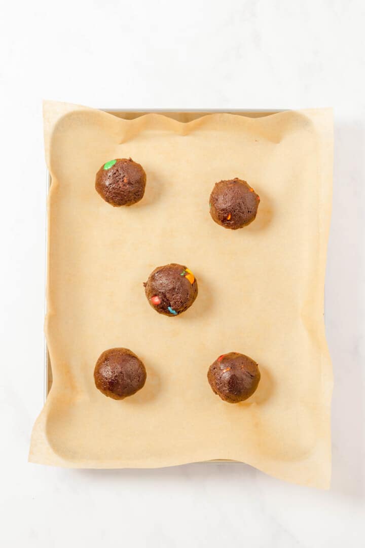 putting the cookie dough balls on baking sheet.