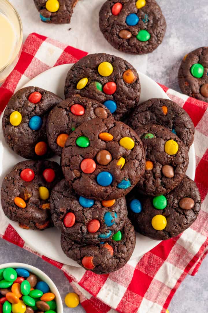 Chocolate M&M Cookies piled on a white plate.