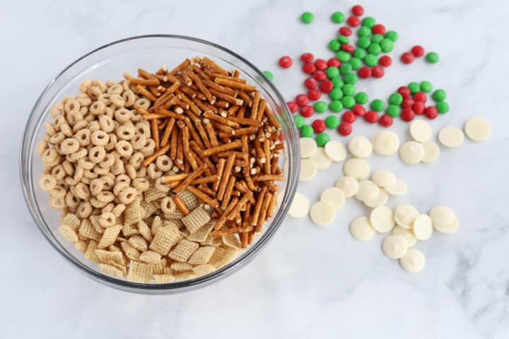 ingredients for Christmas Chex Mix in glass bowl.