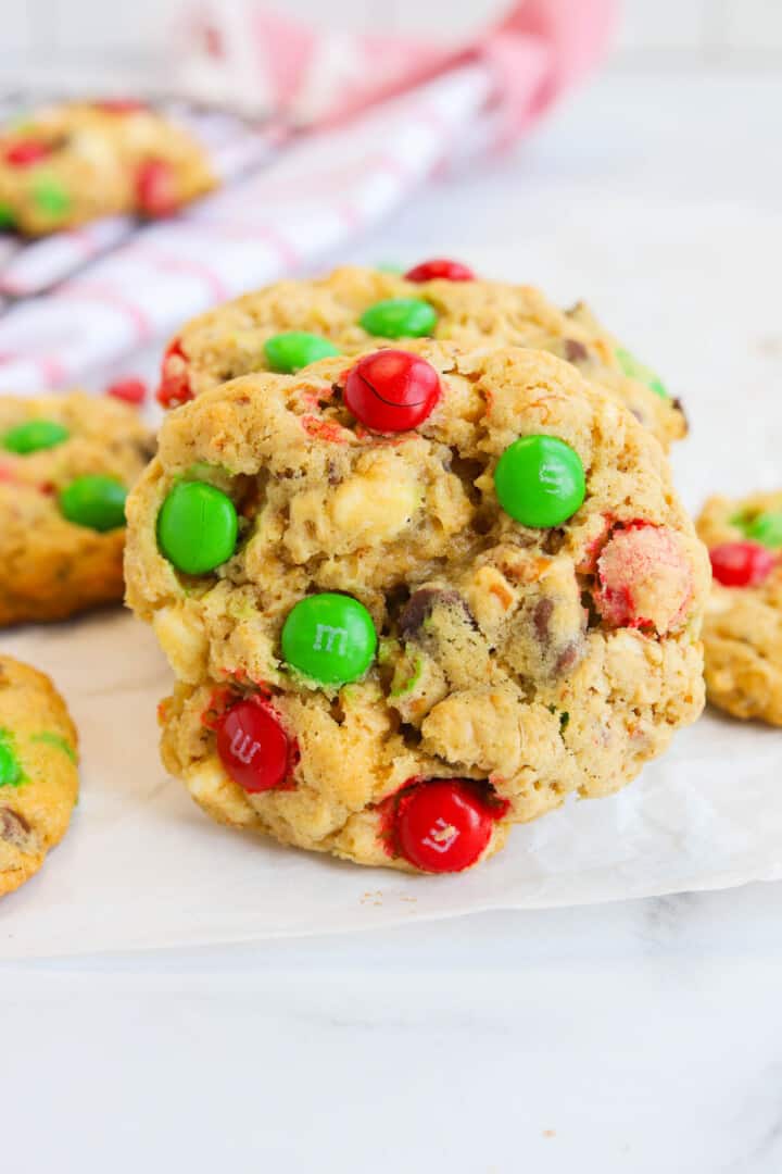 Christmas Monster Cookies stacked on parchment paper.