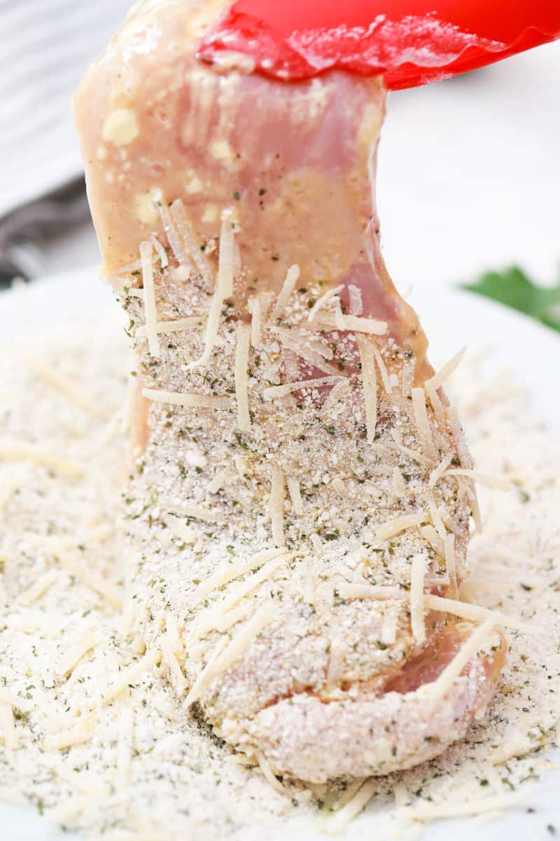 coating chicken with breadcrumbs and cheese.