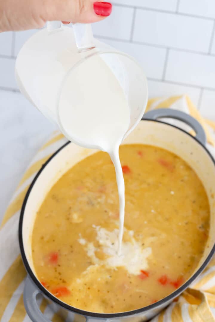adding half and half to the soup.